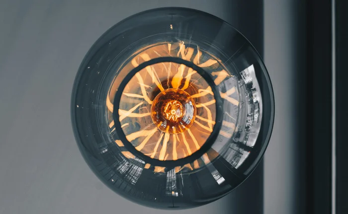 Close-up view of a modern Edison light bulb with glowing orange filaments inside a glass sphere, symbolizing creativity, innovation, and warm industrial design