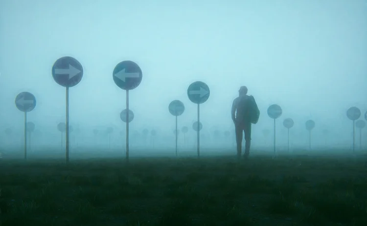 A man walks in fog, surrounded by direction signs pointing in many different directions