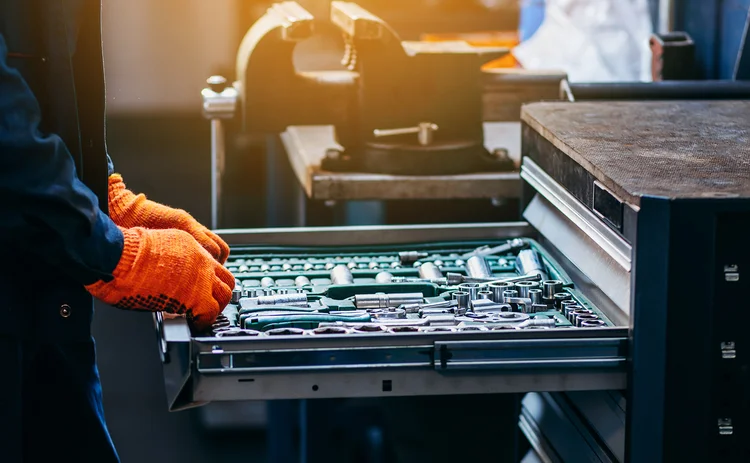 A car mechanic selects tools from a drawer in a garage