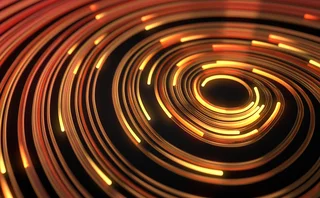 Abstract spiral of glowing orange and yellow light trails on a black background