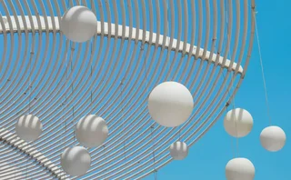 White spherical outdoor lighting installation against a bright blue sky and green trees